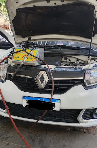 Veículo com capô aberto recebendo manutenção de ar-condicionado na Oficina do Freitas